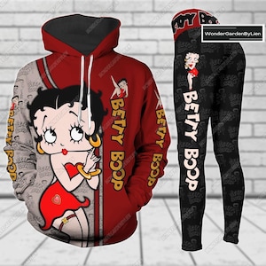 Può includere: Un set di felpa con cappuccio e leggings rosso e nero con un'immagine di cartone animato di Betty Boop. Il set presenta un motivo ripetuto del viso di Betty Boop e le parole "Betty Boop".