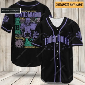 May include: Black baseball jersey with purple trim and the words "Foolish Mortals." The back of the jersey features a Haunted Mansion graphic with the text "Welcome Foolish Mortals." The jersey has a button-up front and short sleeves.