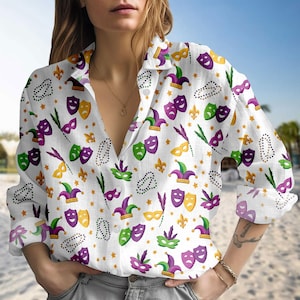 Peut inclure: Chemise blanche à boutons avec un motif répété de masques de Mardi Gras, de chapeaux de bouffon, de fleur de lys et d'étoiles dorées, vertes et violettes. La chemise à manches longues a une coupe décontractée.