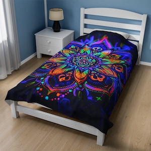 May include: A black twin bed with a colorful mandala patterned duvet cover. The duvet cover features a large, bright orange, yellow, green, and blue mandala design on a black background.