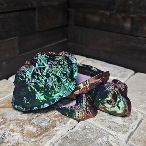 May include: A decorative turtle-shaped trinket box with a hinged lid. The box is made of iridescent green and purple resin with intricate details. The lid is open, revealing a purple interior.