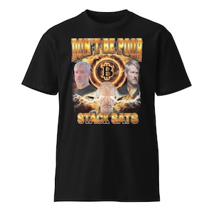 Puede incluir: Camiseta negra con un gráfico de tres hombres frente a un símbolo de Bitcoin. El texto "Don't Be Poor Stack Sats" está impreso en la camiseta.