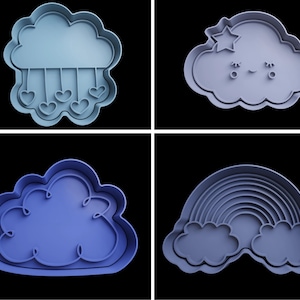 May include: Four blue plastic cookie cutters shaped like clouds, a rainbow, and a cloud with a star and a face.
