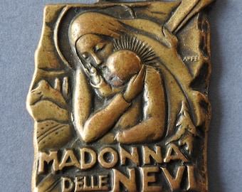 May include: A bronze pendant depicting the Madonna and Child. The pendant is inscribed with the words "Madonna delle Nevi".