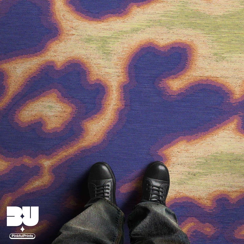 Man standing on an eclectic home decor, the dopamine colorful purple psychedelic area rug, with hand painted abstract cowhide animal print design with faux textile texture in vivid purple, orange, yellow and green hues printed rug 8x10.