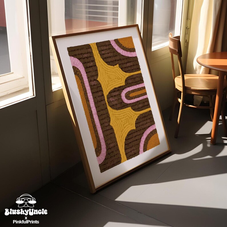 The wood-framed yellow, brown and pink wall art is placed on floor and agist the window in the dorm room. The geometric, colorful and vibrant art print features a tufted rug textured painting by Blushyuncle, perfect for dorm room essentials.