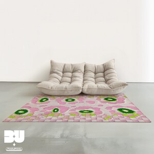 Modern beige modular togo sofa on decorative rug, pastel floral, pink flower carpet, abstract leopard pattern and green checkers patterned rug in minimalist living room.