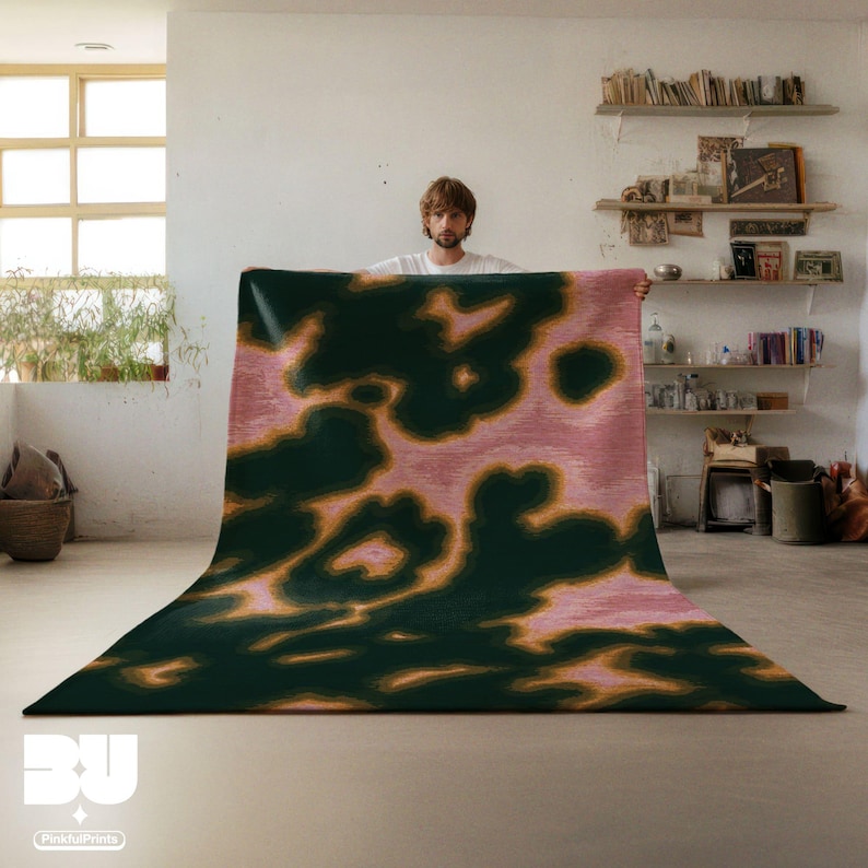Person holding a dopamine decor, Pink Psychedelic Area Rug, with abstract animal print pattern, dark green yellow hues , standing in a cozy room with books and decor on shelves.