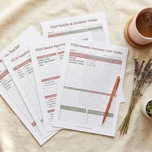 Puede incluir: Un conjunto de hojas de seguimiento blancas para el control del SOPK, que incluyen un rastreador de ciclo hormonal mensual, citas médicas, suplementos y resultados de laboratorio, con detalles impresos en rosa empolvado y verde salvia.
