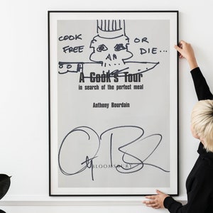 以下が含まれることがあります： アンソニー・ボーデインの「A Cook's Tour」と書かれた額入りのポスター。ポスターには、コック帽とナイフを持った骸骨の白黒イラストが描かれています。著者のサインが下部にあります。