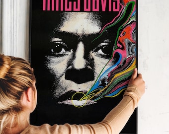 May include: A black and white poster with a close-up of Miles Davis's face. The poster has a colorful abstract design in the background. The text "miles davis" is printed in pink letters at the top of the poster.