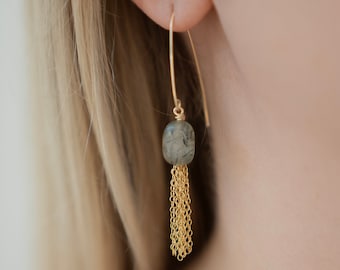 May include: Gold dangle earrings with a gray stone and a gold chain tassel.
