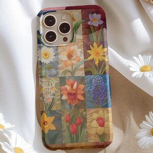 May include: A phone case with a floral design. The case is made of a hard plastic and has a clear back. The flowers are in a variety of colors, including red, yellow, and blue. The case is designed to fit an iPhone 13 Pro.