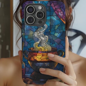 May include: A phone case with a stained glass design featuring a cauldron with smoke rising from it. The background is a dark blue with stars and a purple sky. The case has a camera cutout with three lenses.