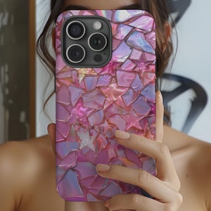May include: A pink and purple iPhone case with a mosaic design. The case is made of a hard plastic material and has a raised camera bump.