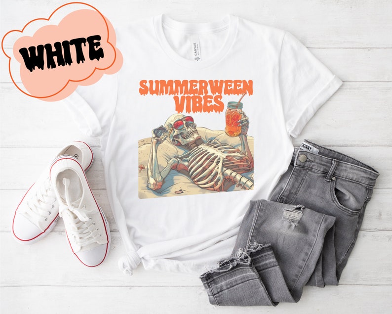 May include: White t-shirt with a graphic of a skeleton wearing sunglasses and holding a glass of orange juice. The text "Summerween Vibes" is printed on the shirt.