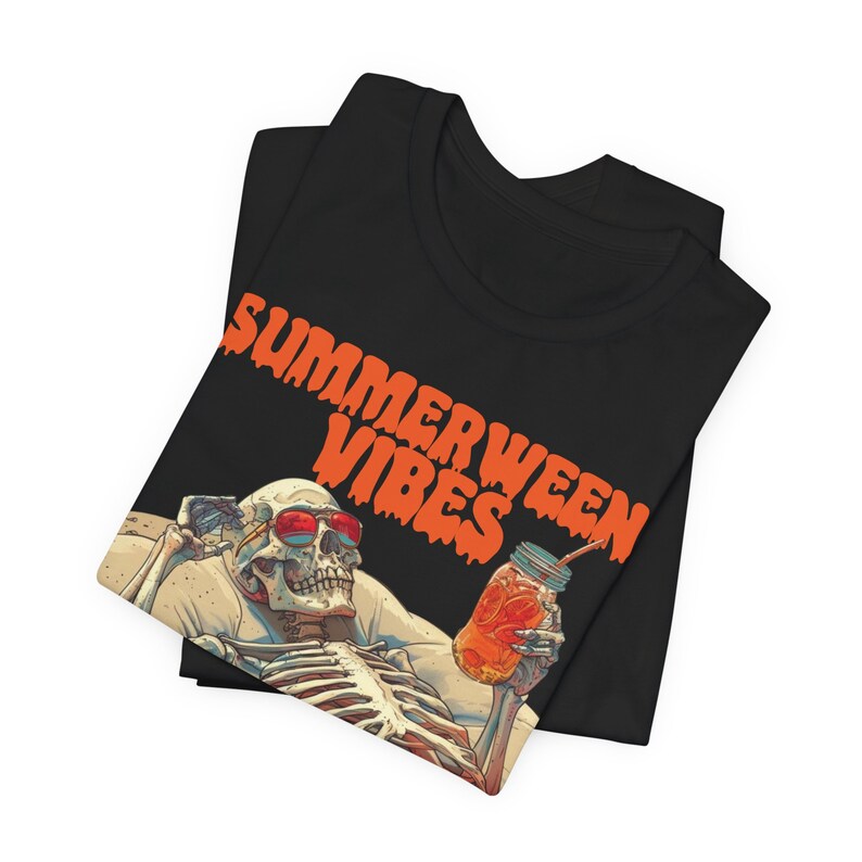 May include: Black t-shirt with an orange graphic of a skeleton wearing sunglasses and holding a mason jar with a straw. The text "SUMMERWEEN VIBES" is written in orange dripping letters.