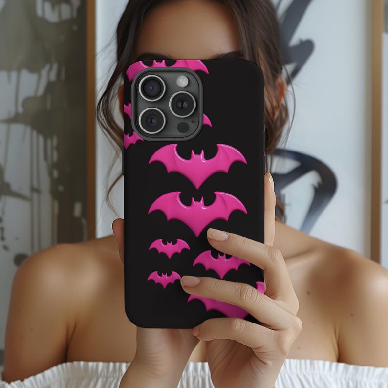 May include: A black phone case with a pink bat pattern. The case has a camera lens cutout and a raised lip around the edges.