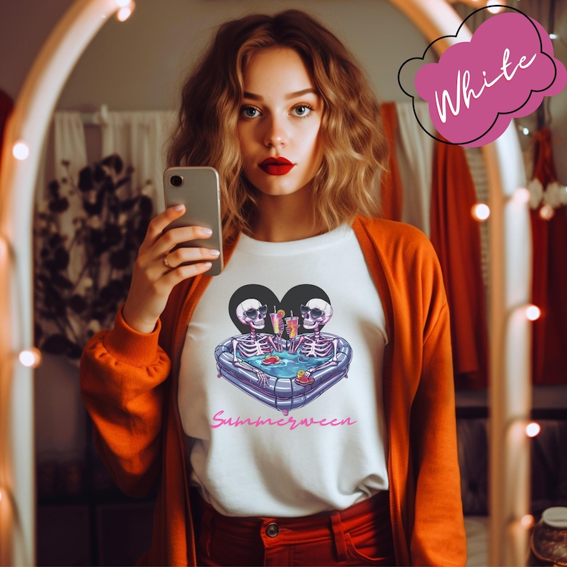 May include: White t-shirt with a graphic of two skeletons in a heart-shaped pool with the text "Summerween".