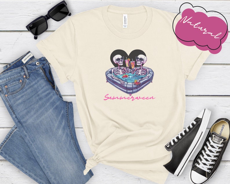 May include: A white t-shirt with a graphic of two skeletons in a heart-shaped inflatable pool with drinks. The text "Summerween" is printed below the graphic.