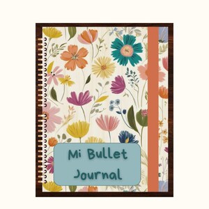 May include: A floral patterned journal with a teal blue cover and a brown spine. The cover has a teal blue rectangle with the text "Mi Bullet Journal" in white.