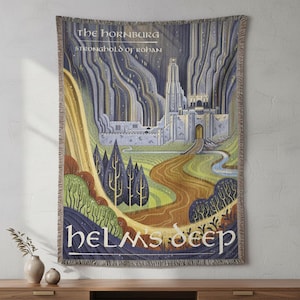 May include: Woven tapestry featuring an illustration of a fortress with the text "The Hornburg, Stronghold of Rohan" and "Helms Deep". The artwork depicts a castle with a winding road, trees, and mountains in shades of blue, green, and brown.