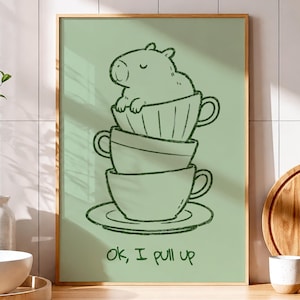 May include: A rectangular wall art print in a wooden frame featuring a sage green background with a dark green line drawing of a capybara sitting inside a stack of three teacups on a saucer, with the text "Ok, I pull up" written below.
