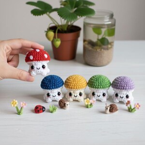 Può includere: Una collezione di cinque piccoli funghi all'uncinetto con gambi bianchi e cappelli rossi, blu, gialli, verdi e viola. Il set include minuscoli accessori all'uncinetto: due lumache marroni, una coccinella rossa e diversi piccoli fiori colorati.