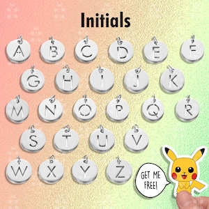 Puede incluir: Una colecci&oacute;n de colgantes iniciales plateados, cada uno con una letra diferente del alfabeto. Los colgantes son redondos con un peque&ntilde;o lazo en la parte superior para sujetarlos a una cadena o pulsera. La palabra "Initials" est&aacute; en la parte superior. Una pegatina de Pikachu est&aacute; en la esquina.