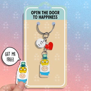 May include: A keychain featuring Finn and Jake from Adventure Time. The keychain is on a card that says "Open the door to happiness".
