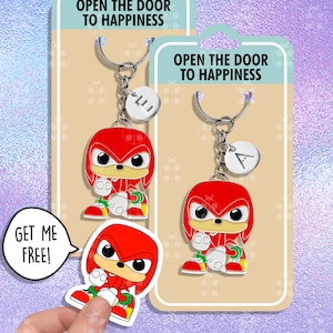 May include: Two red and white cartoon character keychains with silver key rings and charms. The charms are round and have the letters "E" and "A" on them. The keychains are on a white background with the text "Open the door to happiness" on the top. A sticker of the same cartoon character is on the bottom left corner with the text "Get me free!" in a speech bubble.