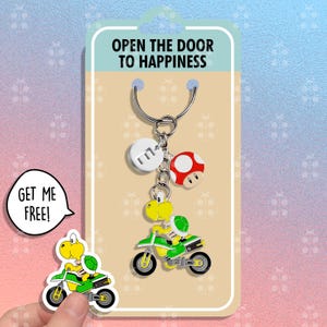 May include: A novelty keychain featuring a green and yellow cartoon character riding a motorcycle, a red and white mushroom, and a white disc with the letter "E". The packaging reads "OPEN THE DOOR TO HAPPINESS".