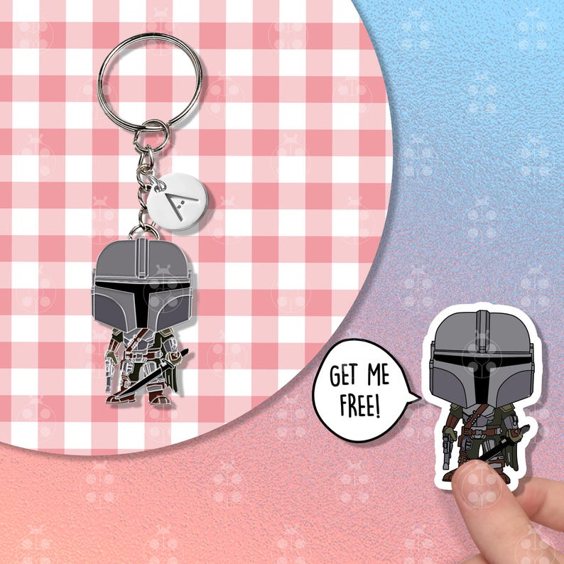 Puede incluir: Un llavero de Mandaloriano con un dise&ntilde;o de personaje estilizado. El llavero tiene un anillo plateado y un peque&ntilde;o dije blanco con la letra "A". La figura del Mandaloriano es en tonos grises, verdes y marrones. El fondo es un patr&oacute;n de cuadros rosas y blancos.