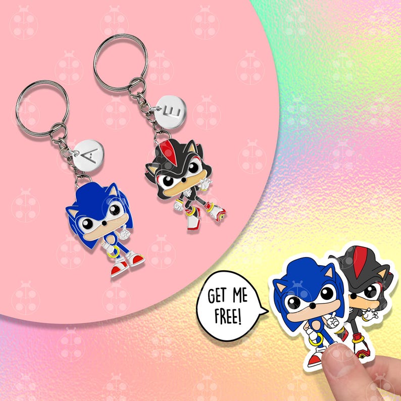 Puede incluir: Dos llaveros con personajes de dibujos animados, uno azul y otro negro con detalles rojos, cada uno unido a un llavero plateado. El llavero del personaje azul tiene la letra "A" en un dije blanco. El llavero del personaje negro tiene las letras "LI" en un dije blanco. Un bocadillo dice "GET ME FREE!"