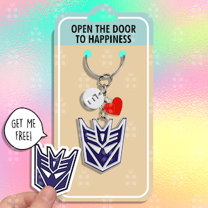 May include: A keyring with a blue and white emblem, a red heart, and a white circle with the letter "E". The keyring is attached to a card with the text "OPEN THE DOOR TO HAPPINESS". A sticker with the same emblem and the text "GET ME FREE!" is also present.