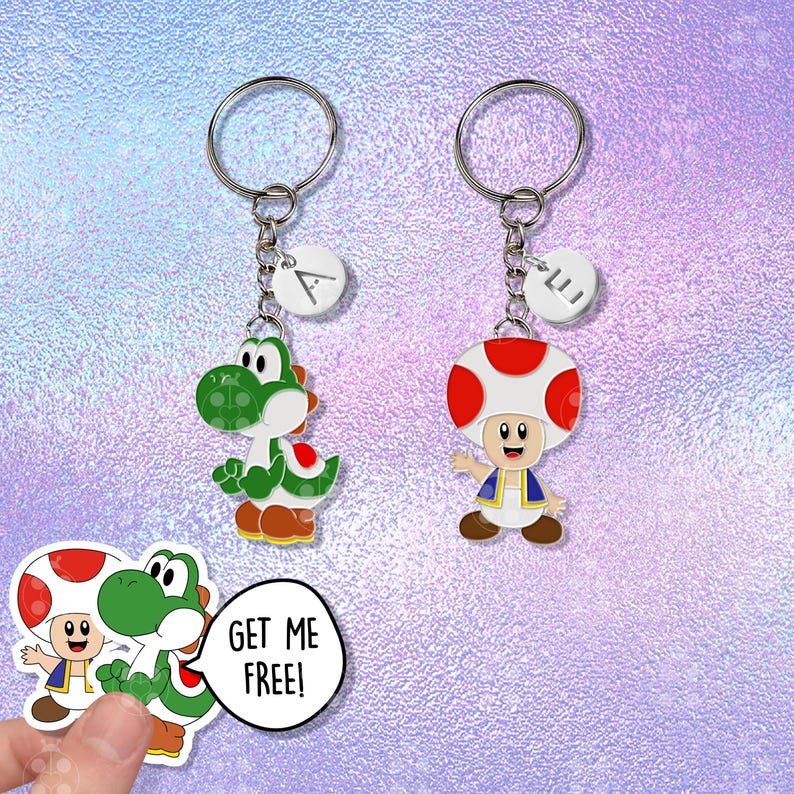 Puede incluir: Dos llaveros con los personajes de dibujos animados Yoshi y Toad de la serie de videojuegos Super Mario. El llavero de Yoshi es verde y blanco, y el llavero de Toad tiene una gorra de hongo roja y blanca. Cada llavero tiene un anillo plateado y un dije blanco con una letra.