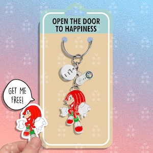 May include: A red and green cartoon character keychain with the text "Open the door to happiness" and "Get me free!" on a white card with a white background.