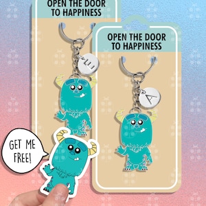 Puede incluir: Dos llaveros de monstruo azul y verde con anillos de llave plateados y dijes de letras. Los dijes están en una tarjeta con el texto "Abre la puerta a la felicidad". Una pegatina del dije de monstruo está en la tarjeta con el texto "¡Consiguelo gratis!"