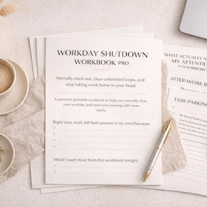 Könnte beinhalten: Eine Büroszene mit einem "WORKDAY SHUTDOWN WORKBOOK PRO", einer Kaffeetasse, einem Stift und Schreibwaren. Das Arbeitsbuch soll Benutzern helfen, ihren Arbeitstag mental abzuschließen. Die Szene befindet sich auf einer neutral getönten Oberfläche.