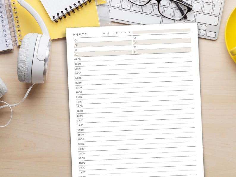 May include: A white paper planner with the word "HEUTE" at the top, featuring a schedule layout with time slots from 7:00 to 19:00. The planner is on a light wood surface, with a keyboard, glasses, and headphones in the background.