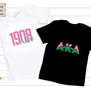 May include: Two t-shirts, one white and one black, with the letters AKA in pink and green. The white shirt has the year 1908 printed in pink above the letters AKA.