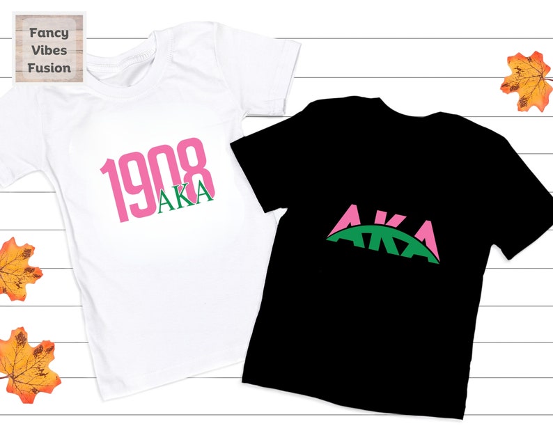 May include: Two t-shirts, one white and one black, with the letters AKA in pink and green. The white shirt has the year 1908 printed in pink above the letters AKA.