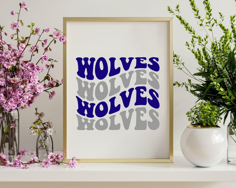 May include: A framed print featuring the word "WOLVES" in a layered, wavy design. The top and third instances of the word are in a deep blue, while the second and fourth are in grey. The frame is gold, and the background is white.