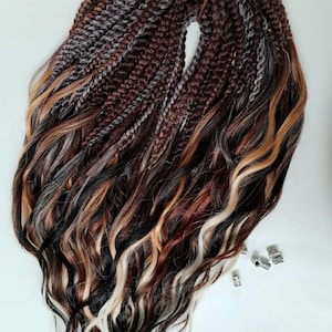 May include: A bundle of braided hair extensions in various shades of brown, gray, black, and blonde. The extensions are wavy at the ends and include small silver-colored metal beads.