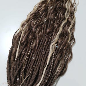 May include: Brown and blonde synthetic dreadlocks with white stitching. The dreadlocks are wavy and have a natural look.