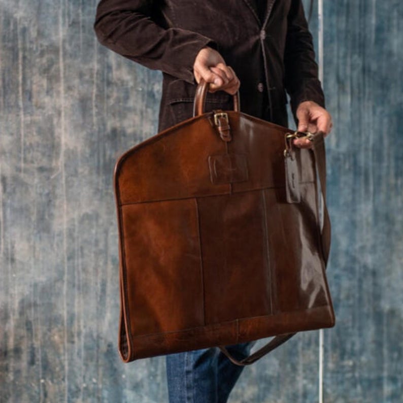 Travel-ready leather garment bag with a sleek design, perfect for hanging suits. Great for groomsmen, Christmas gifts, and as a durable accessory for men.