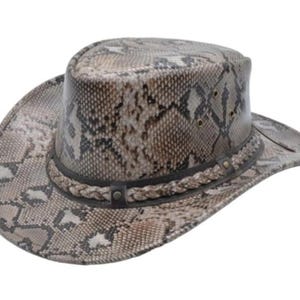 Puede incluir: Un sombrero de vaquero con un estampado de piel de serpiente en tonos marrón, beige y gris. El sombrero presenta una banda trenzada alrededor de la corona y una banda de cuero. Tiene un ala ancha y una copa redonda. El sombrero es de cuero.