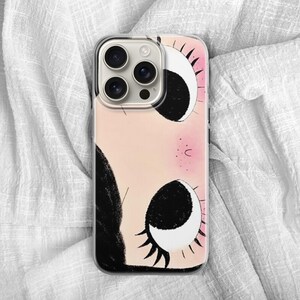Może przedstawiać: Etui na telefon z abstrakcyjną ilustracją twarzy. Projekt przedstawia duże oczy w czerni i bieli na r&oacute;żowym tle. Etui ma przezroczysty obszar na obiektyw aparatu.