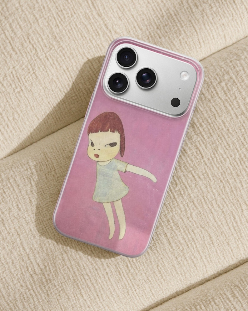Op de afbeelding: Transparante telefoonhoes met een roze achtergrond met een illustratie van een meisje met kort bruin haar en een lichtblauwe jurk. De hoes heeft een zilveren cameramodule.