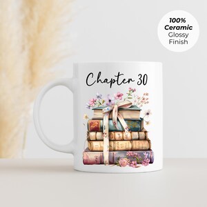 May include: White ceramic mug with a stack of books and floral accents. The mug features the text "Chapter 30" in black script. A decorative ribbon is tied around the books. The mug has a glossy finish.